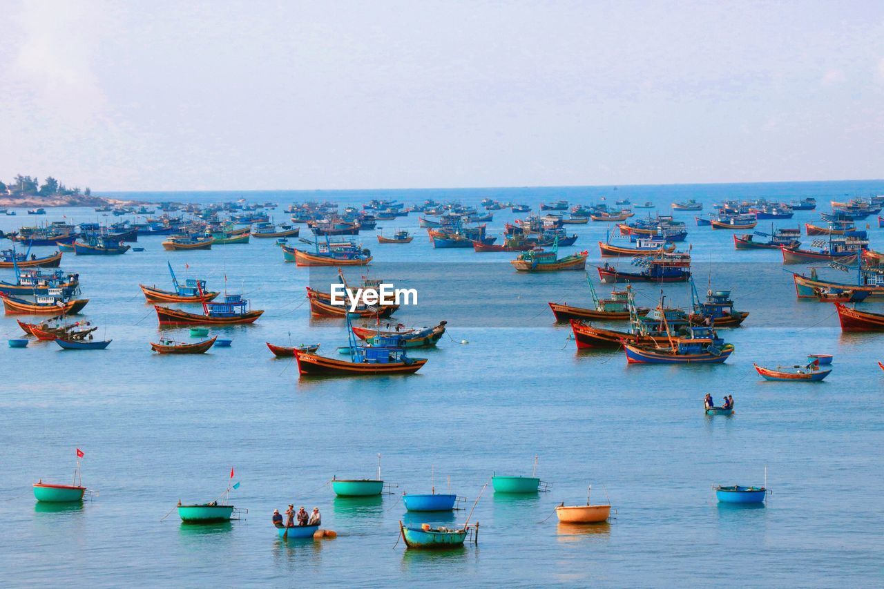 Fishing boats anchored on river against clear sky