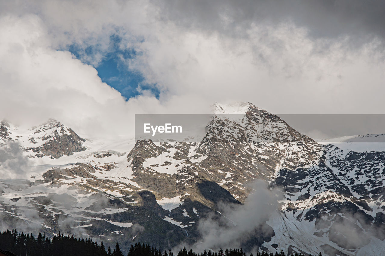 Snowy peaks in alpine mountains landscape with clouds at les-contamines-montjoie, france.