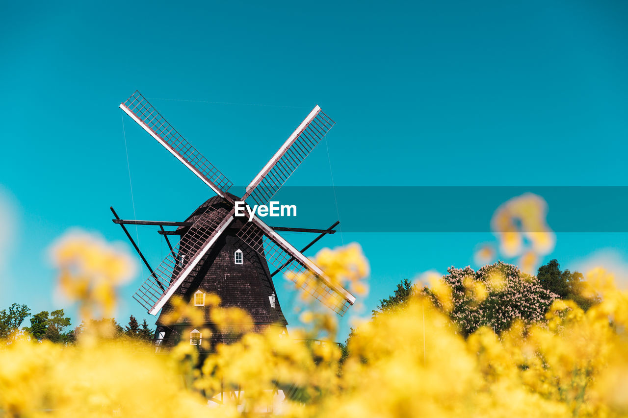 LOW ANGLE VIEW OF WIND TURBINES ON FIELD AGAINST SKY