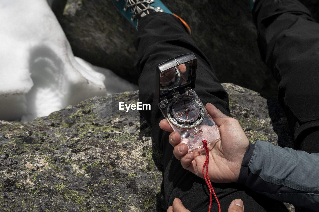 Closeup contemporary compass in women's hand in mountains with snow