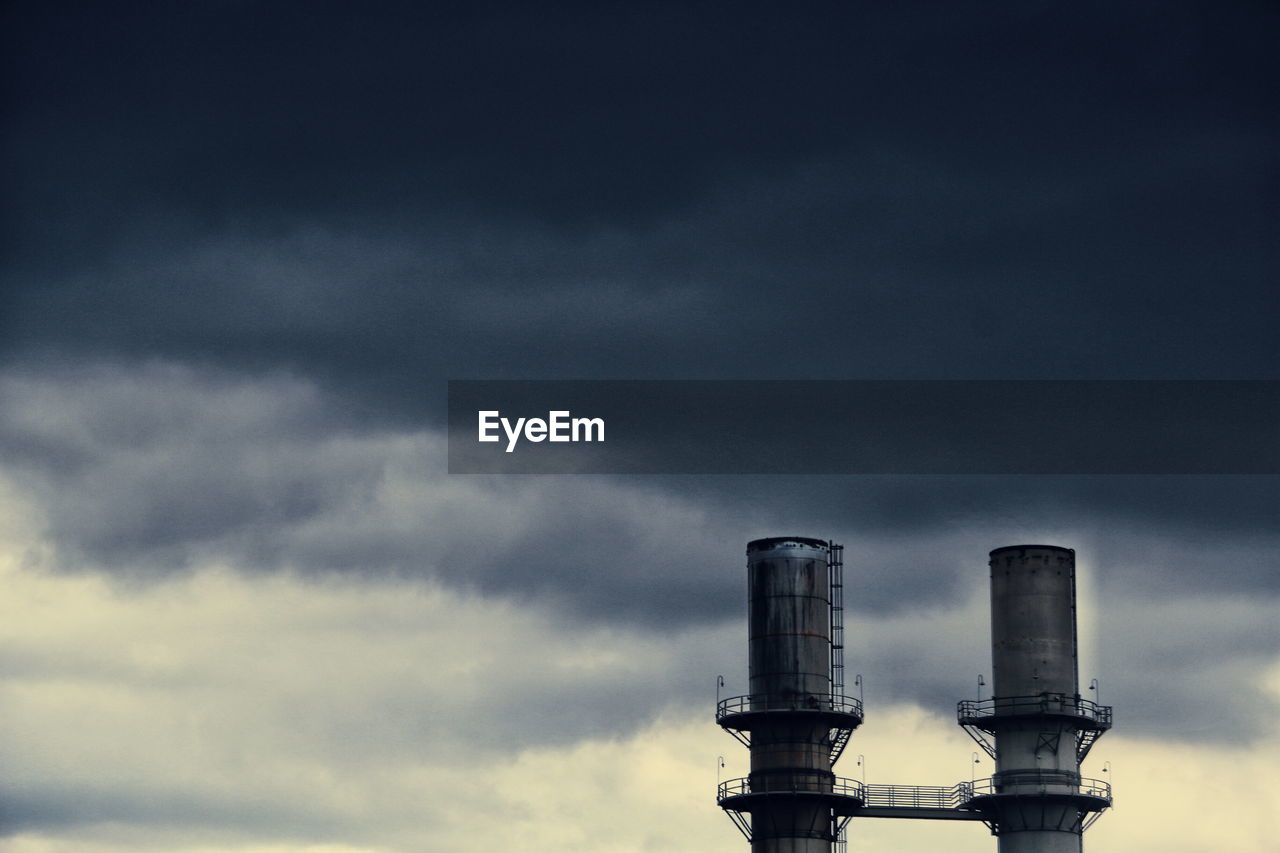 Low angle view of silos against cloudy sky at dusk