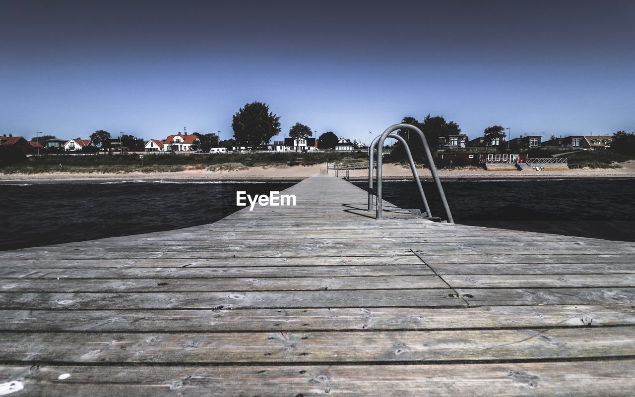 Surface level of wooden pier on sea against clear sky