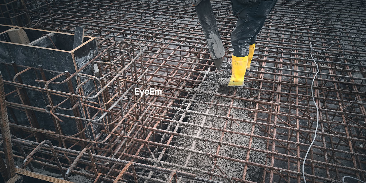 Construction worker dressed in uniform pour concrete to formwork.cement works on a construction site