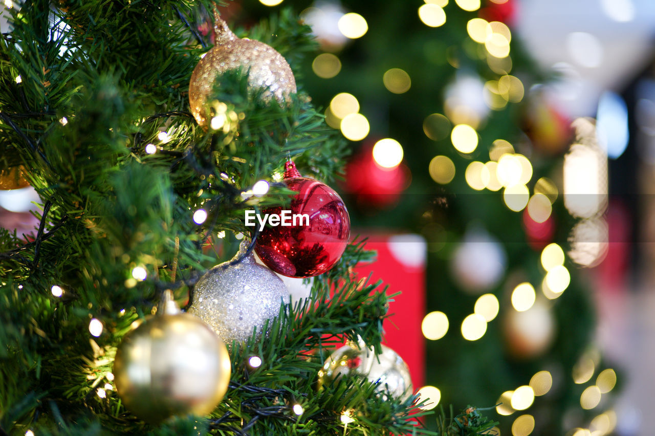 Selective focus on the redball decorated on the christmas tree with the bokeh lights in background.