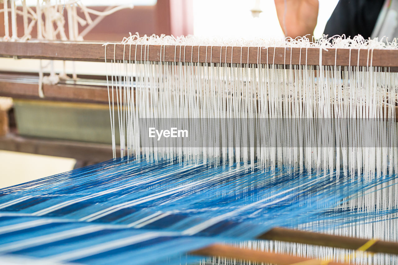 Worker weaving loom in factory