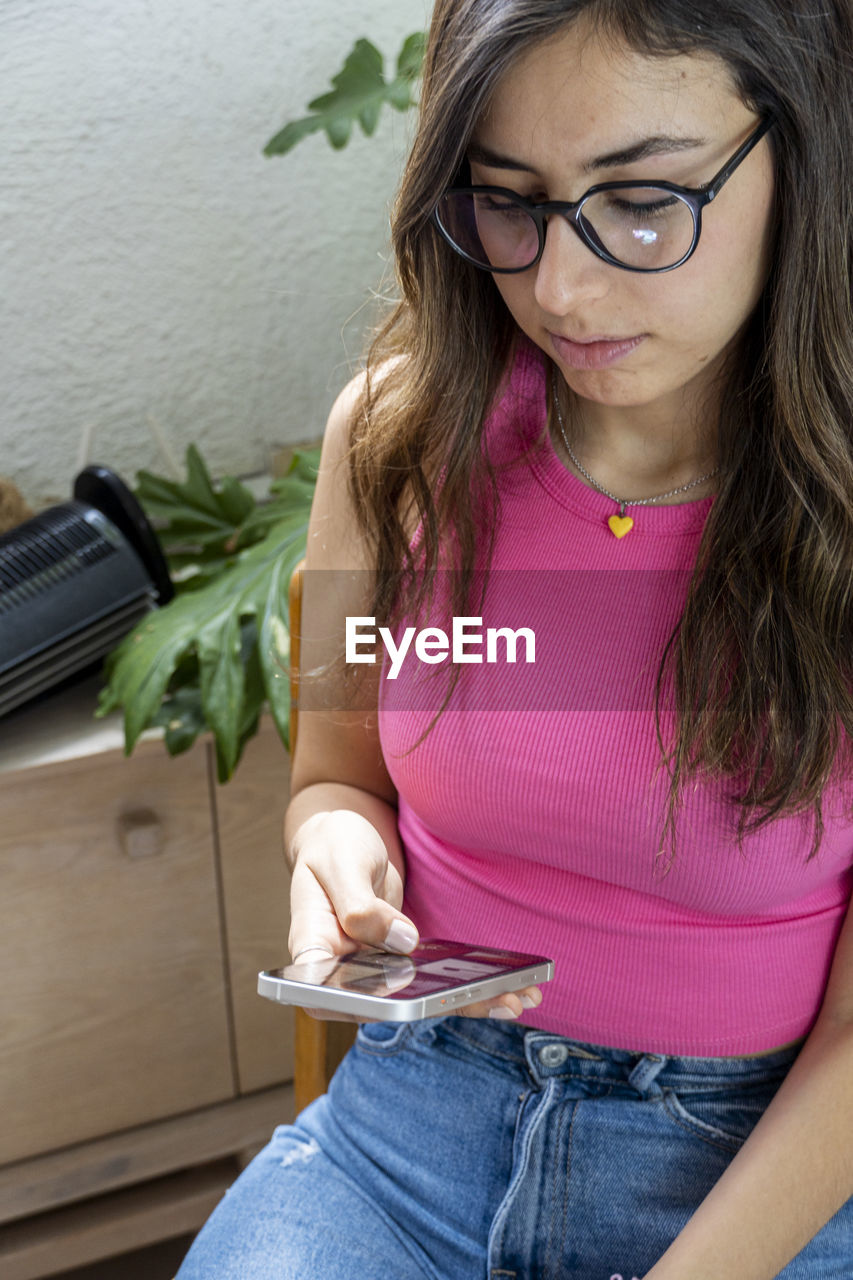 Young hispanic woman, looking at her cell phone checking her social networks