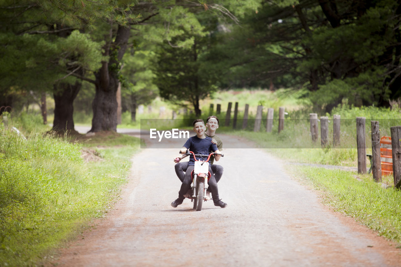 Brothers riding dirt bike on road