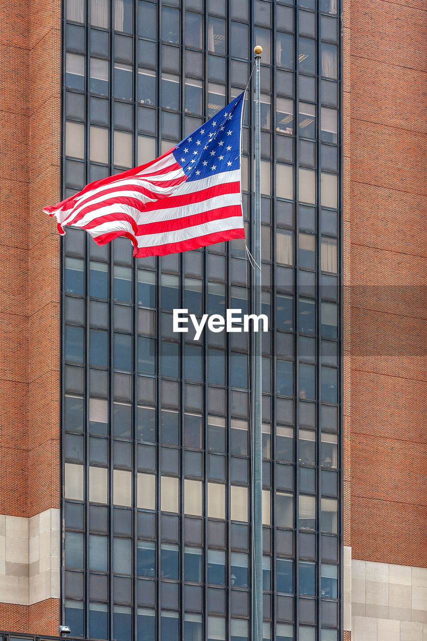 flag, patriotism, architecture, building exterior, striped, built structure, building, no people, day, city, star shape, shape, office building exterior, red, low angle view, pride, blue, outdoors, window covering, symbolism, symbol, facade, nature, window, national icon, emotion