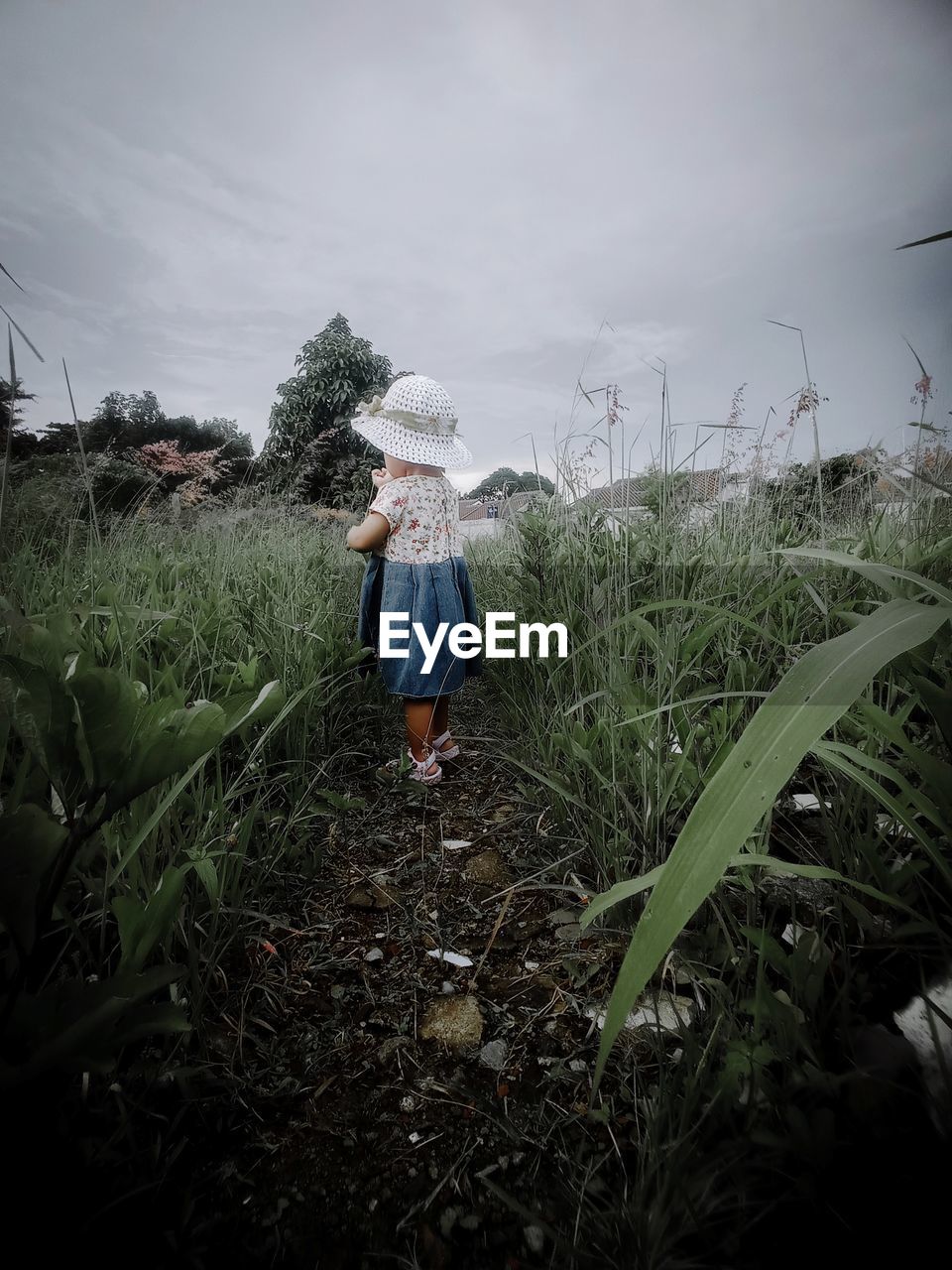 REAR VIEW OF WOMAN STANDING ON FIELD