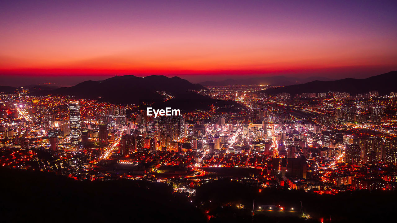 Aerial view of illuminated cityscape during sunset