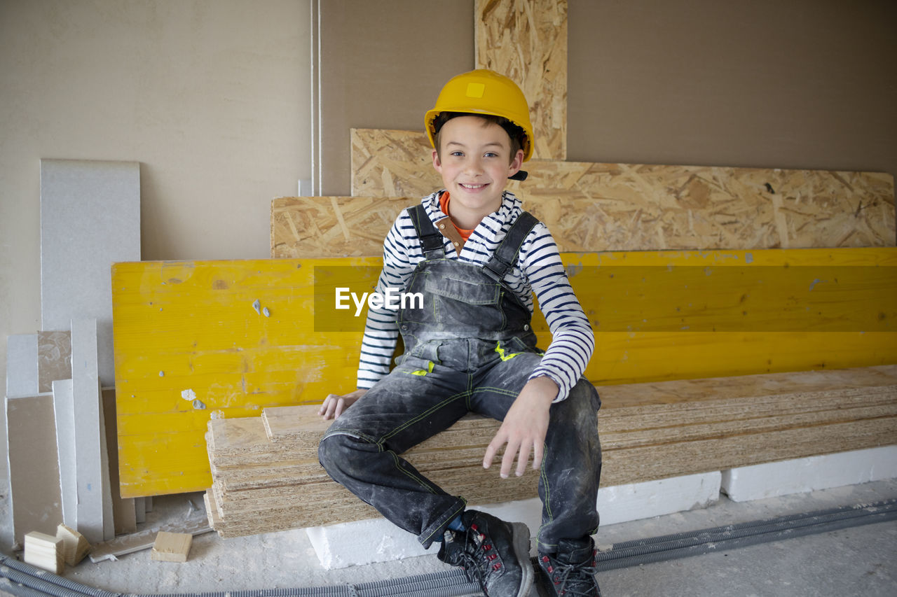 portrait of young man using phone while standing against wall