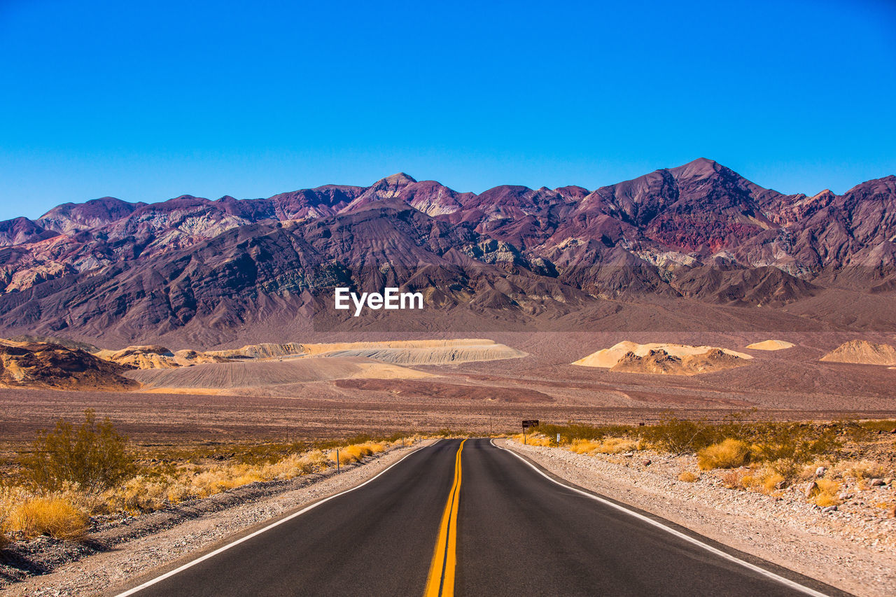 Road leading towards mountains against sky