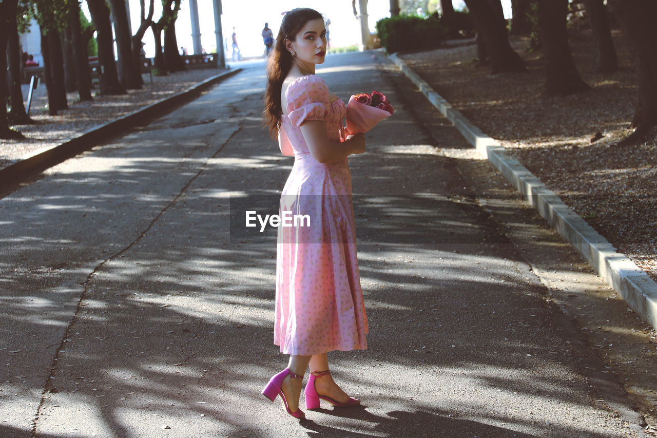 Photoshot of me wearing a pink dress and holding flowers