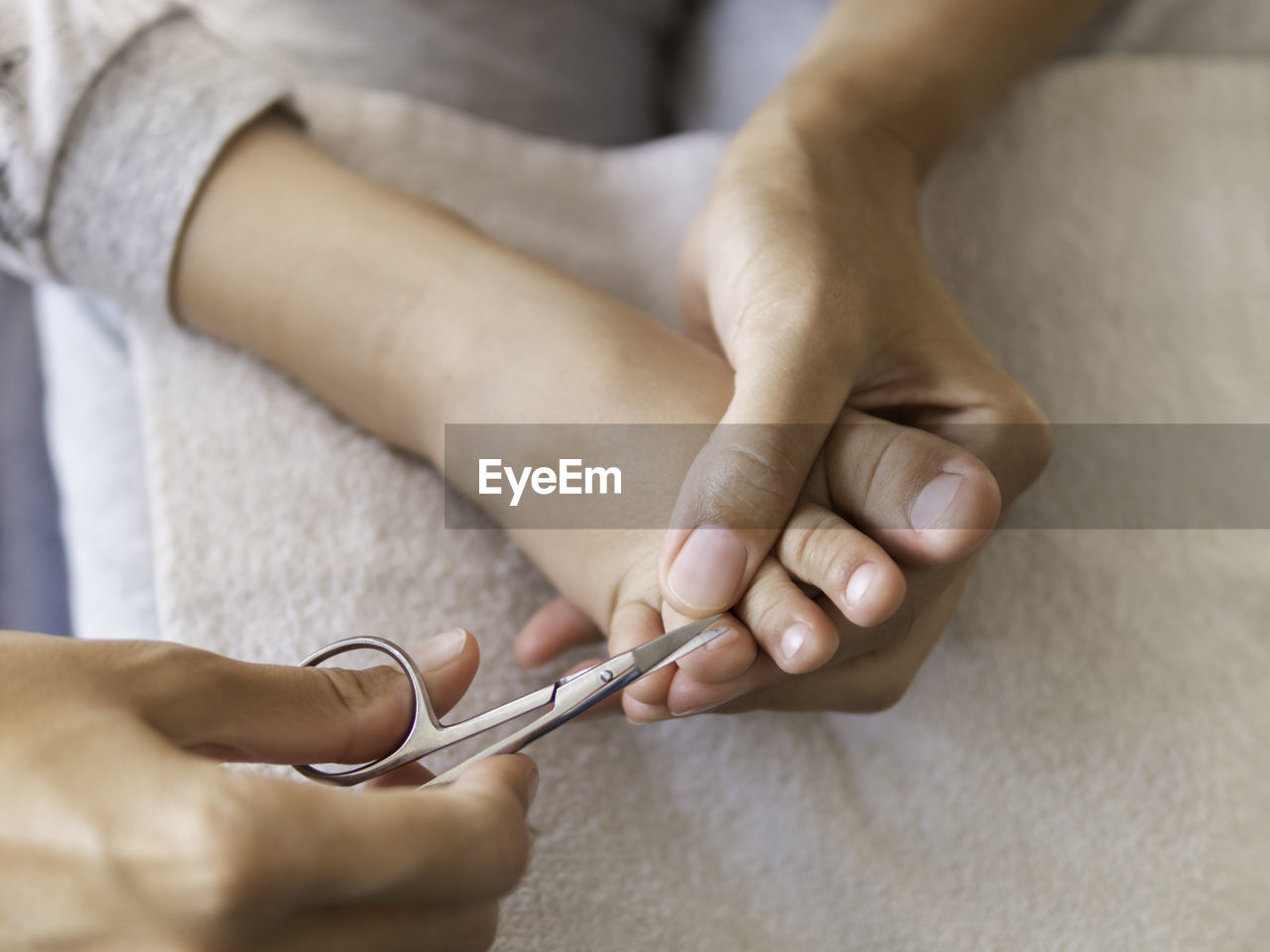 Mother cuts nails on her child's foot fingers. health care procedure at home. pedicure for kid.