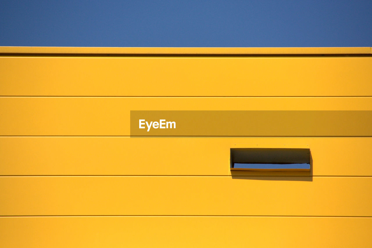 LOW ANGLE VIEW OF YELLOW ORANGE WALL AGAINST SKY