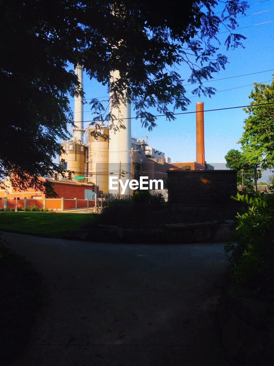 Power plant by road against blue sky