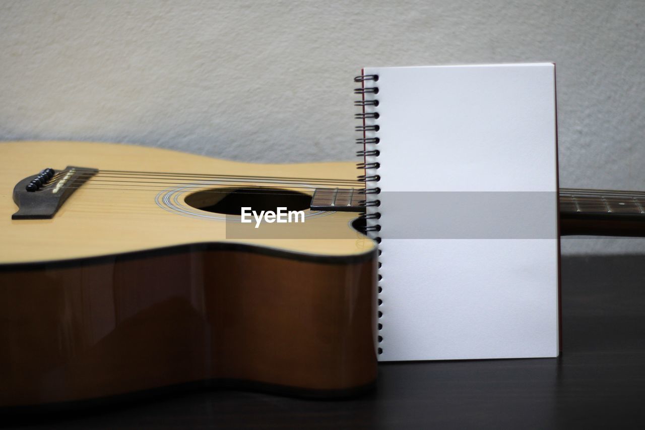 HIGH ANGLE VIEW OF GUITAR ON TABLE AGAINST WALL