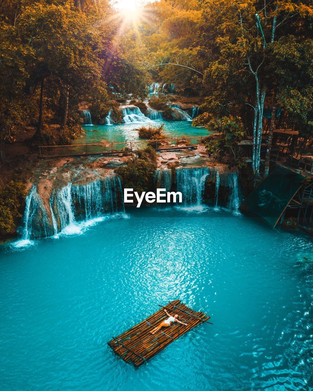 Girl lying on a bamboo raft in the middle if a waterfall in the philippines 