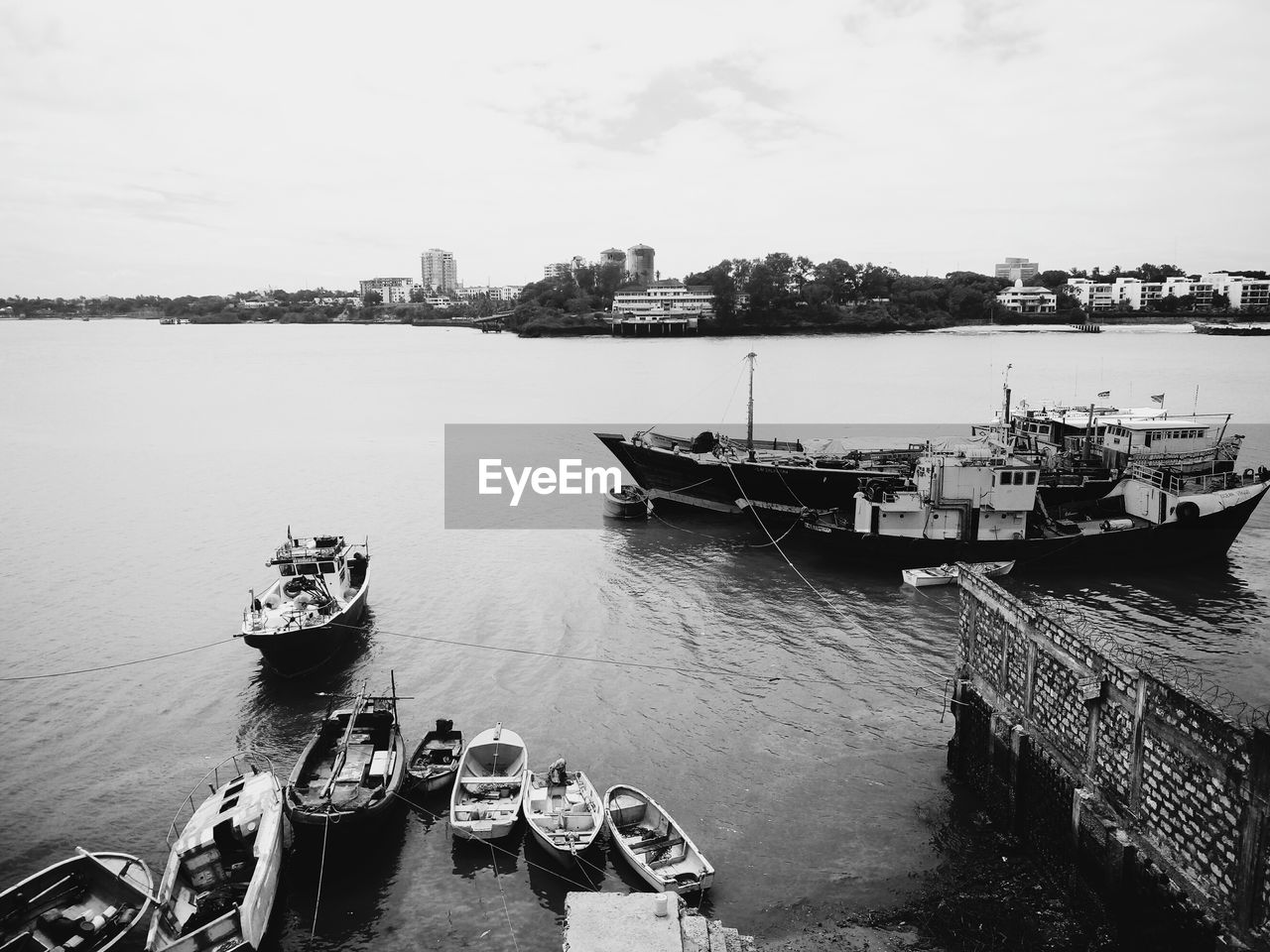 BOATS MOORED IN HARBOR AGAINST SKY