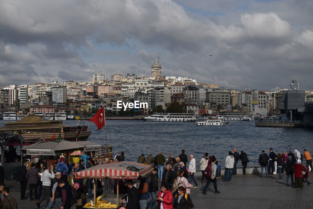 GROUP OF PEOPLE IN RIVER AGAINST CITYSCAPE