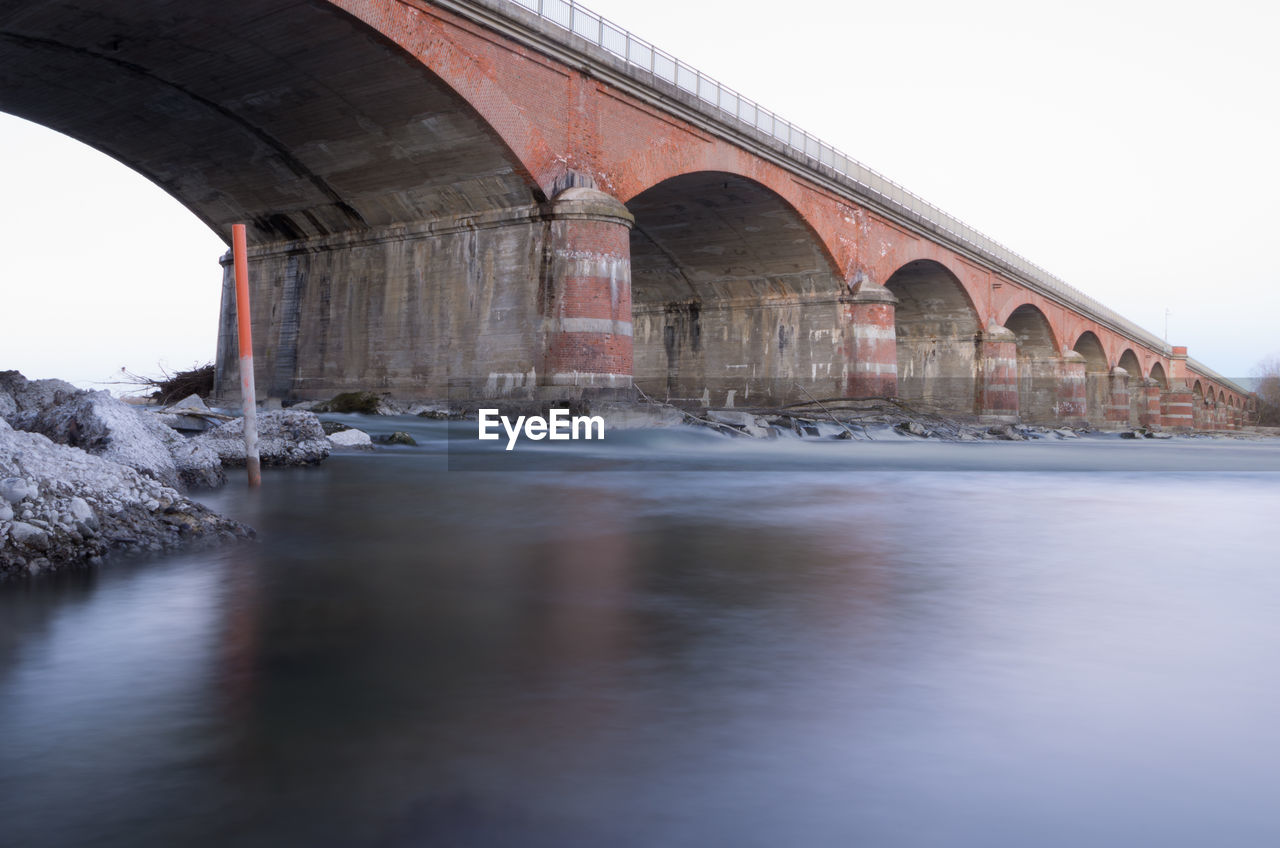 Arch bridge over river against clear sky