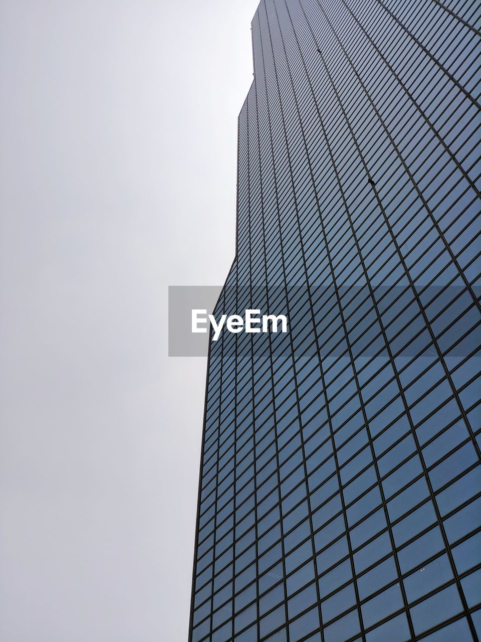 LOW ANGLE VIEW OF MODERN GLASS BUILDING AGAINST CLEAR SKY