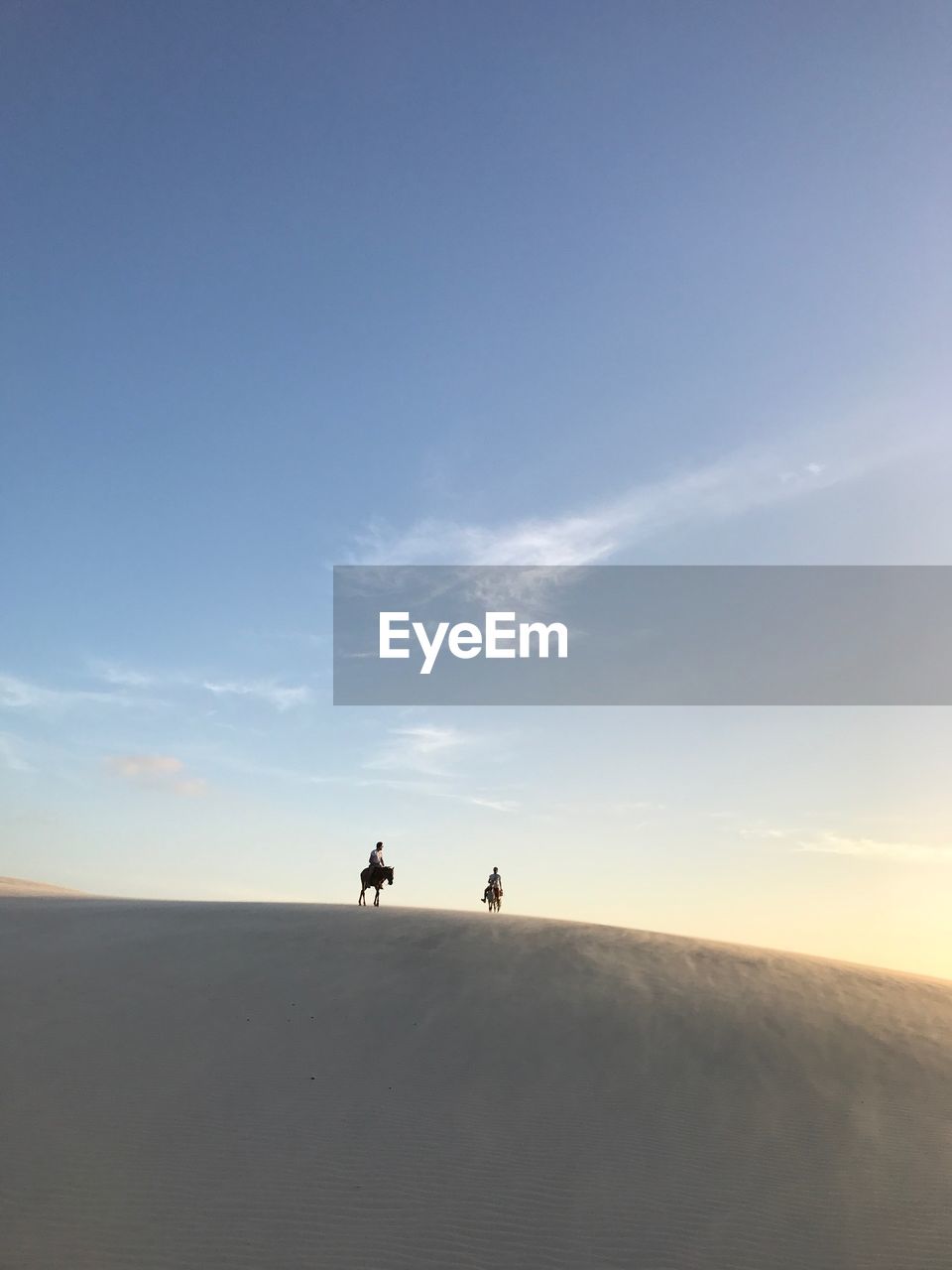 SILHOUETTE PEOPLE WALKING ON SAND DUNE AGAINST SKY