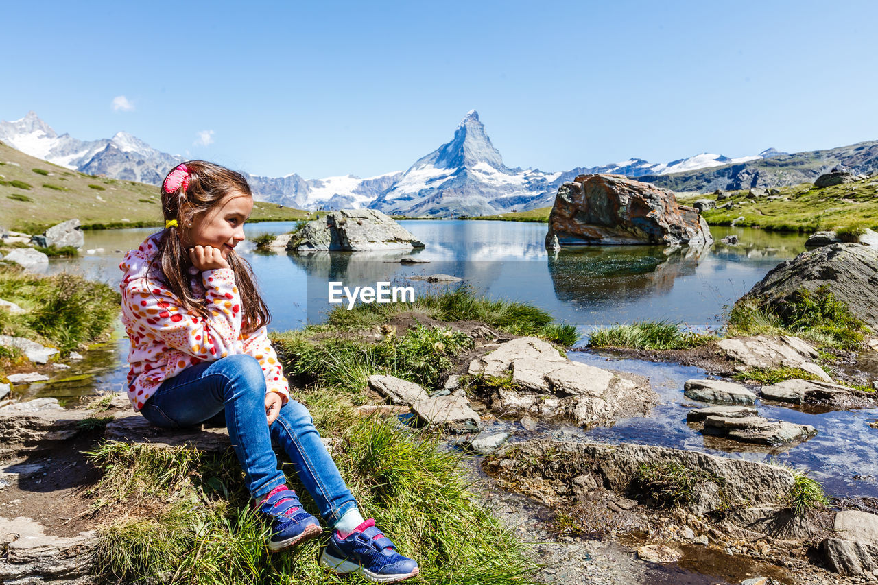 full length of young woman sitting on rock against mountain