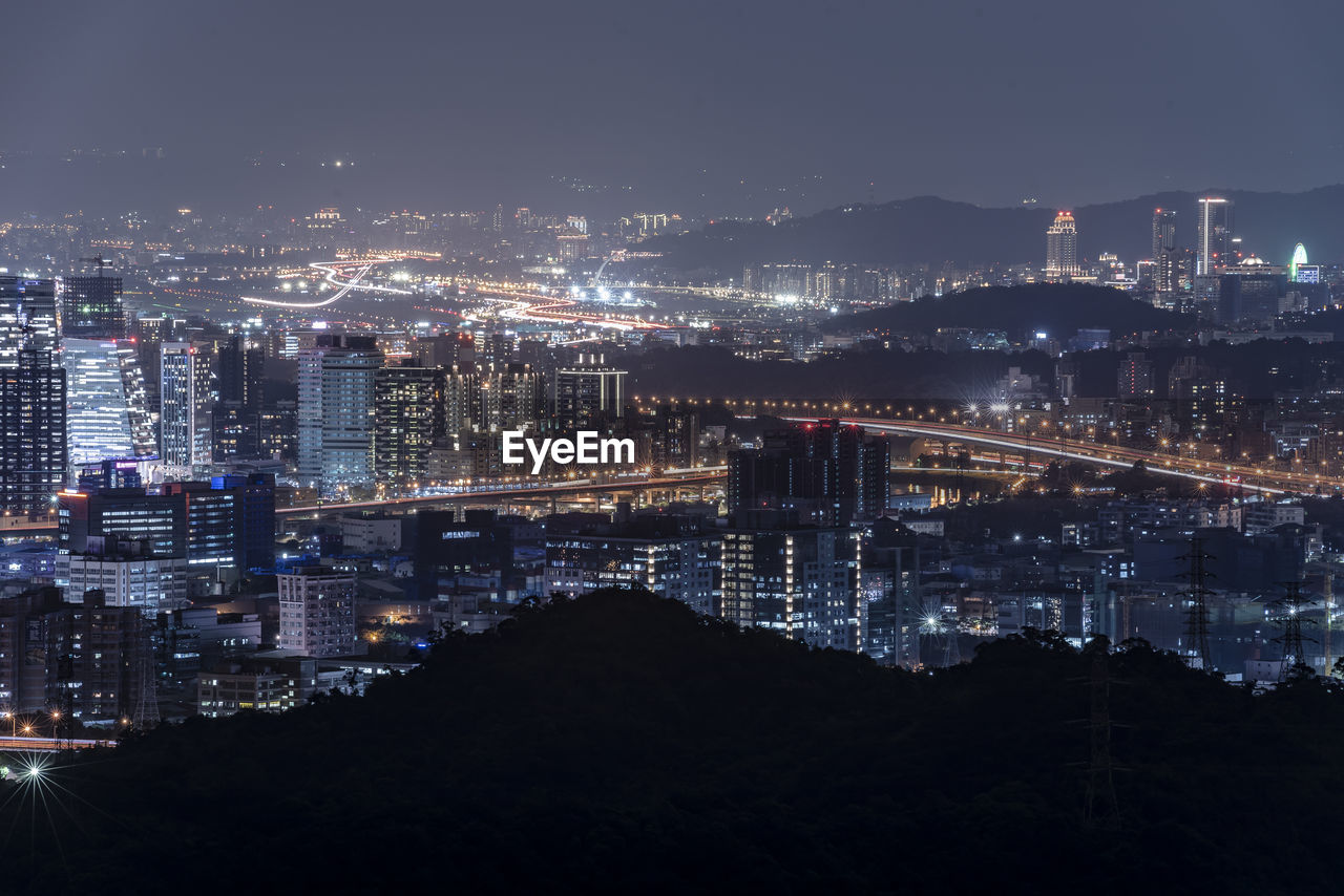 Aerial view of illuminated buildings against sky at night