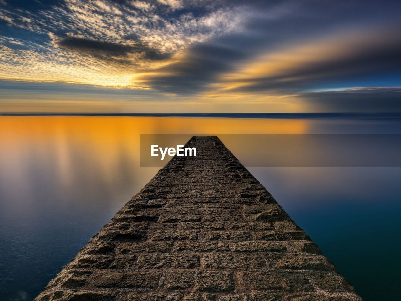 Pier over lake against sky during sunset