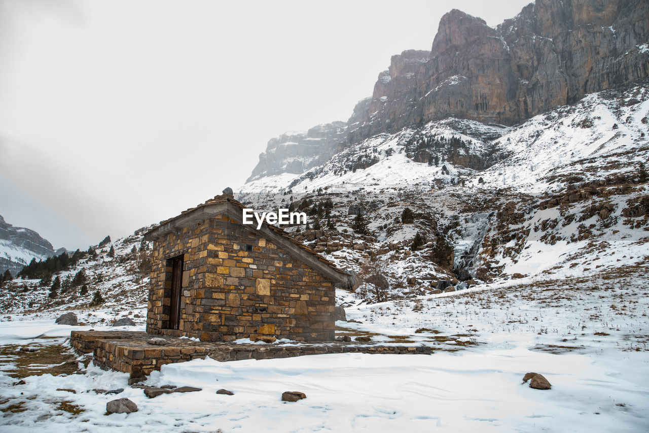 Built structure on snow covered mountain against sky