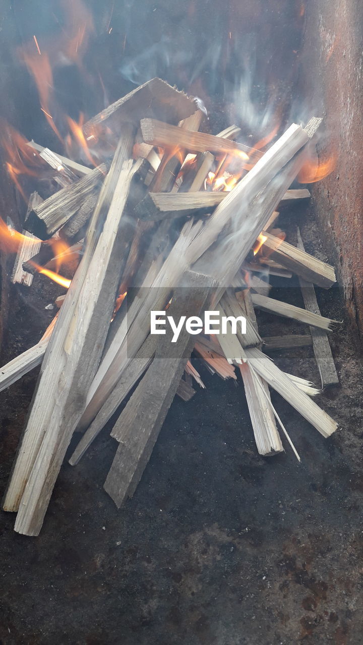 HIGH ANGLE VIEW OF BONFIRE ON WOODEN FLOOR