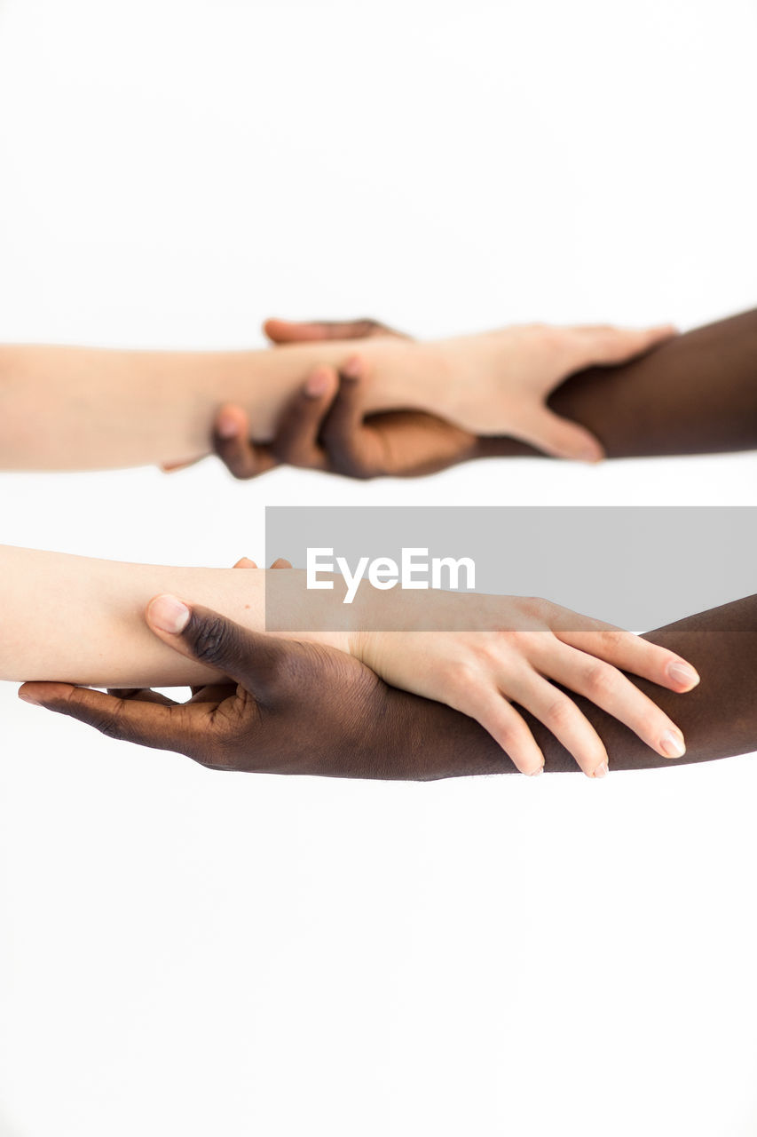 Close-up of couple holding hands over white background