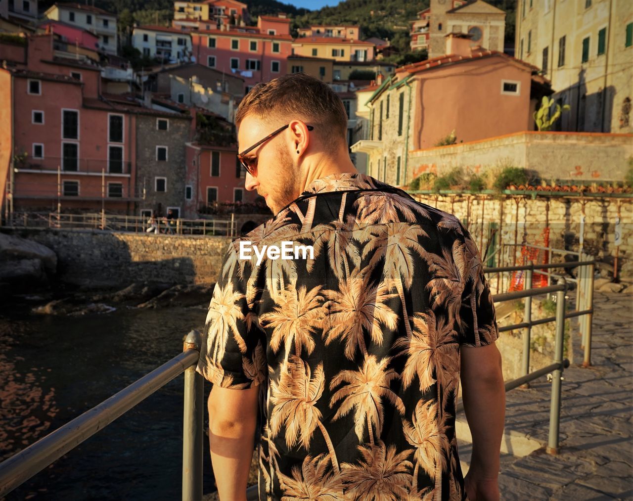 Rear view of man standing by canal in city