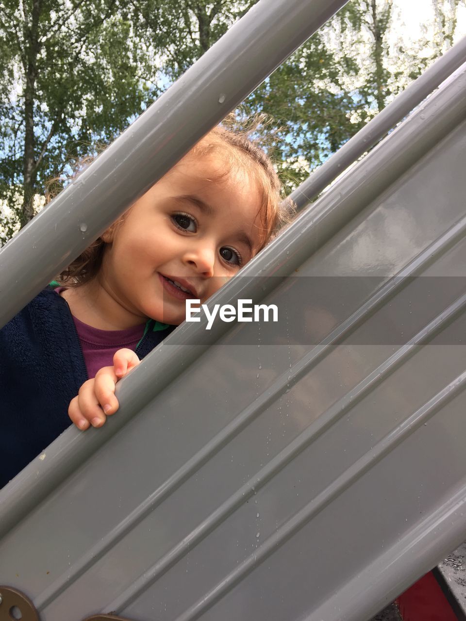Portrait of cute girl looking through gray metallic railing