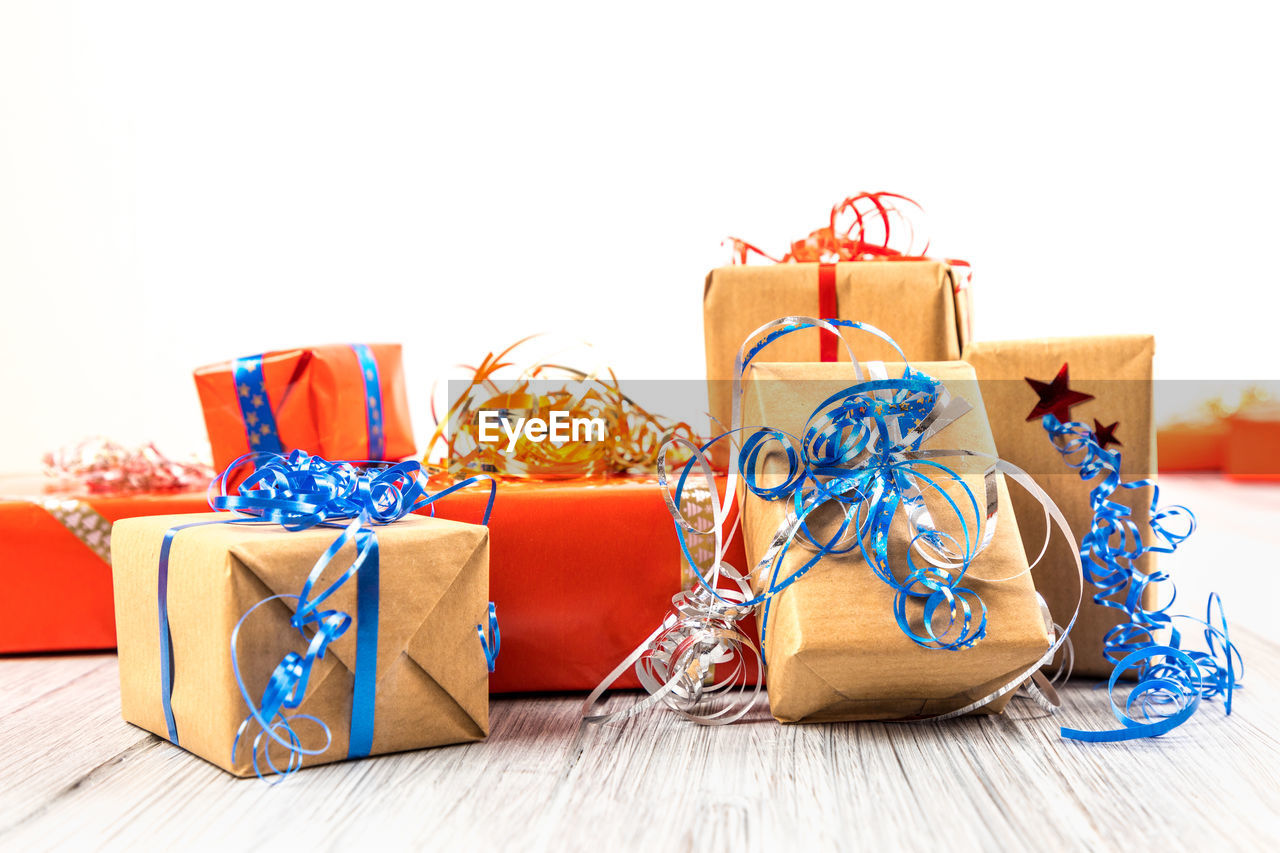 Close-up of christmas presents on wooden table against white background