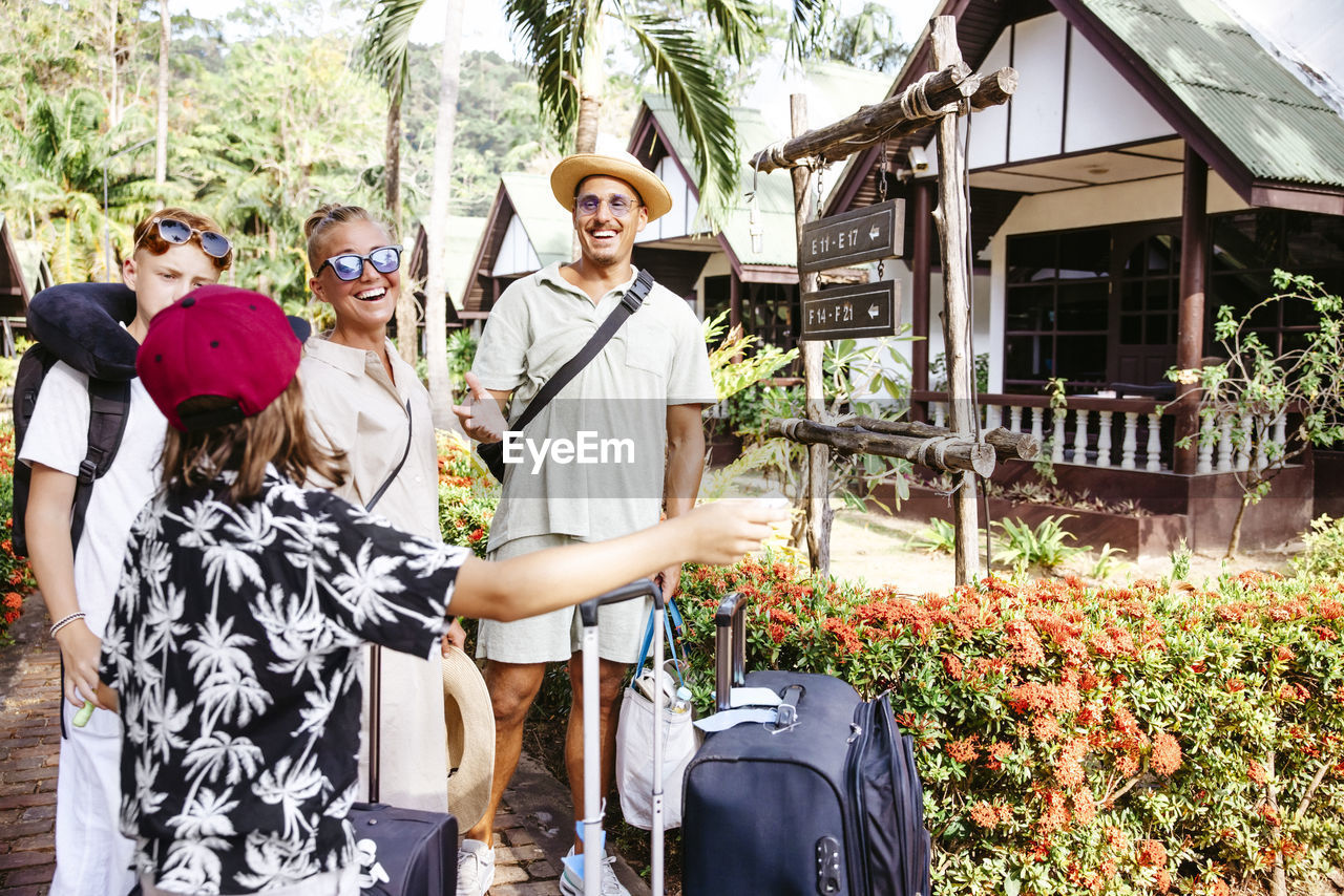 Happy family with luggage arriving at tourist resort during vacation
