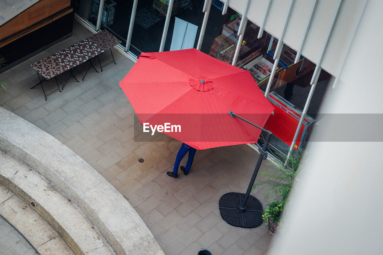 High angle view of person standing below red parasol