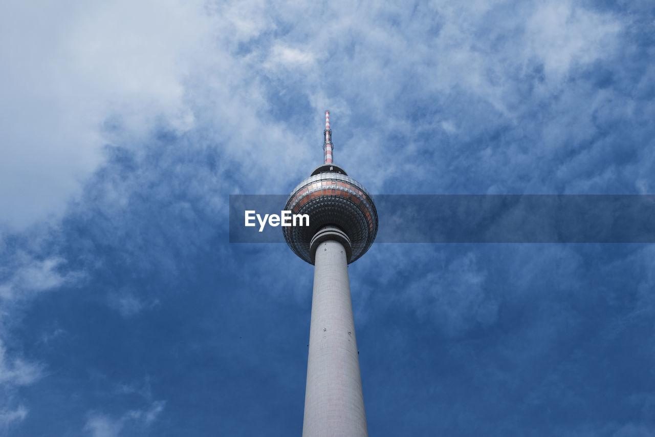 Low angle view of communications tower against cloudy sky