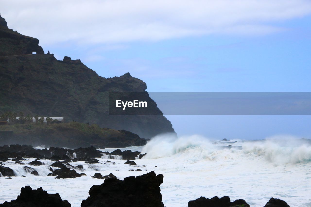 SCENIC VIEW OF ROCKY BEACH AGAINST SKY