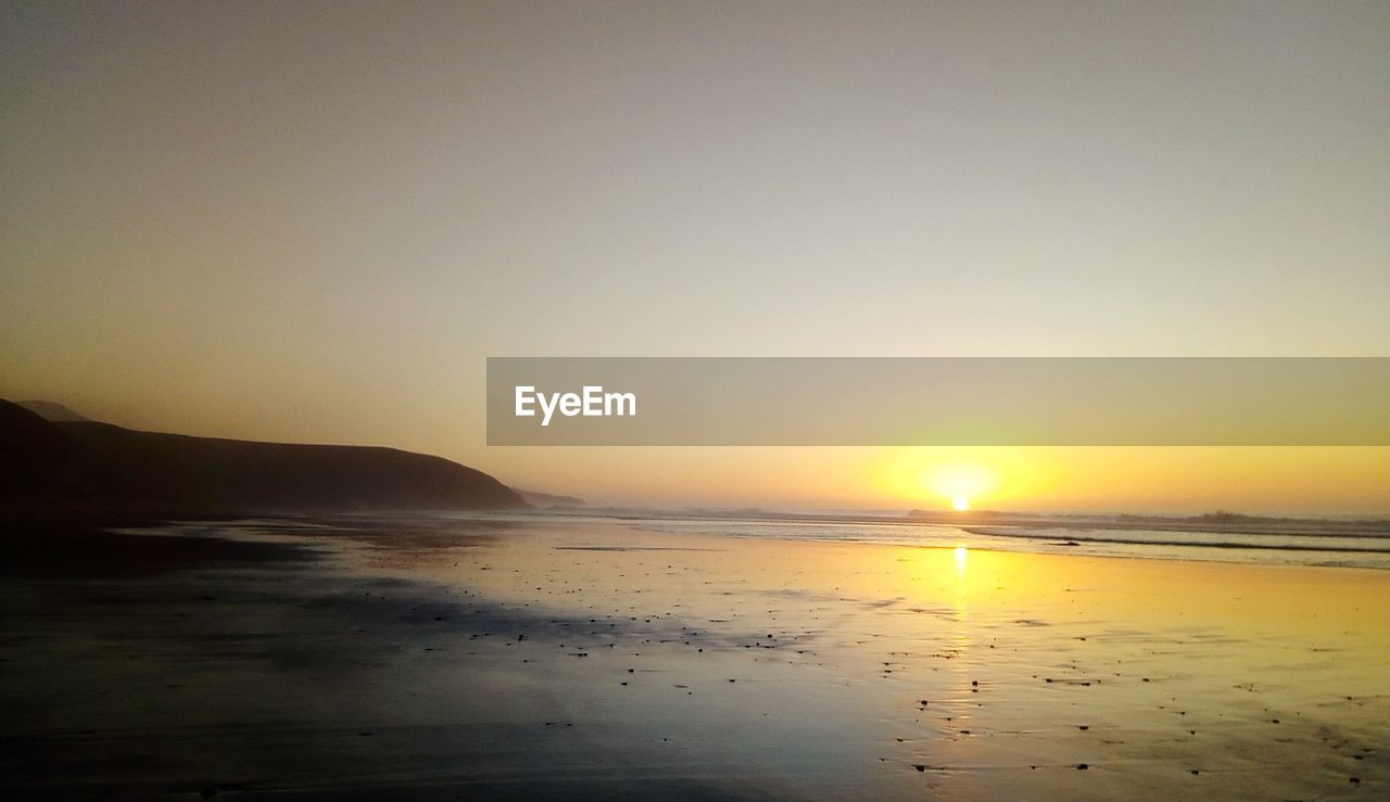 SCENIC VIEW OF BEACH AGAINST SKY DURING SUNSET