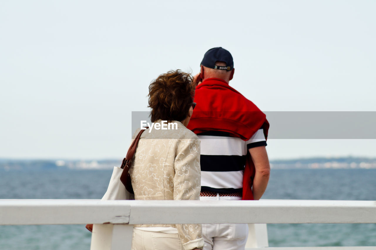 Man and woman standing at railing against sea