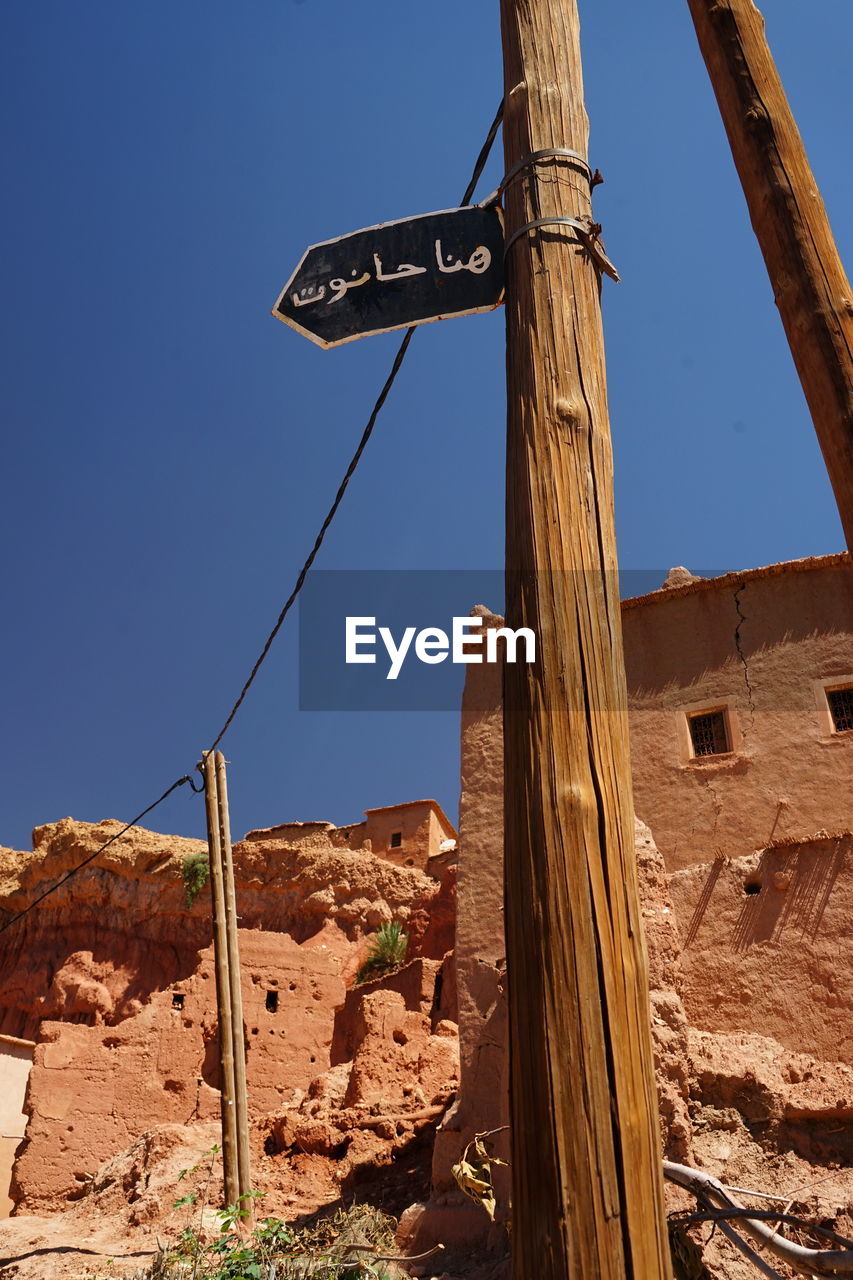sky, nature, architecture, clear sky, blue, no people, built structure, low angle view, wall, day, outdoors, communication, sign, wood, building exterior, sunny, travel destinations, sunlight, travel