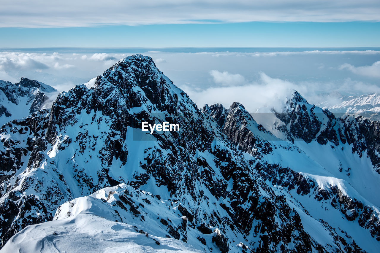 Scenic view of snowcapped mountains against cloudy sky