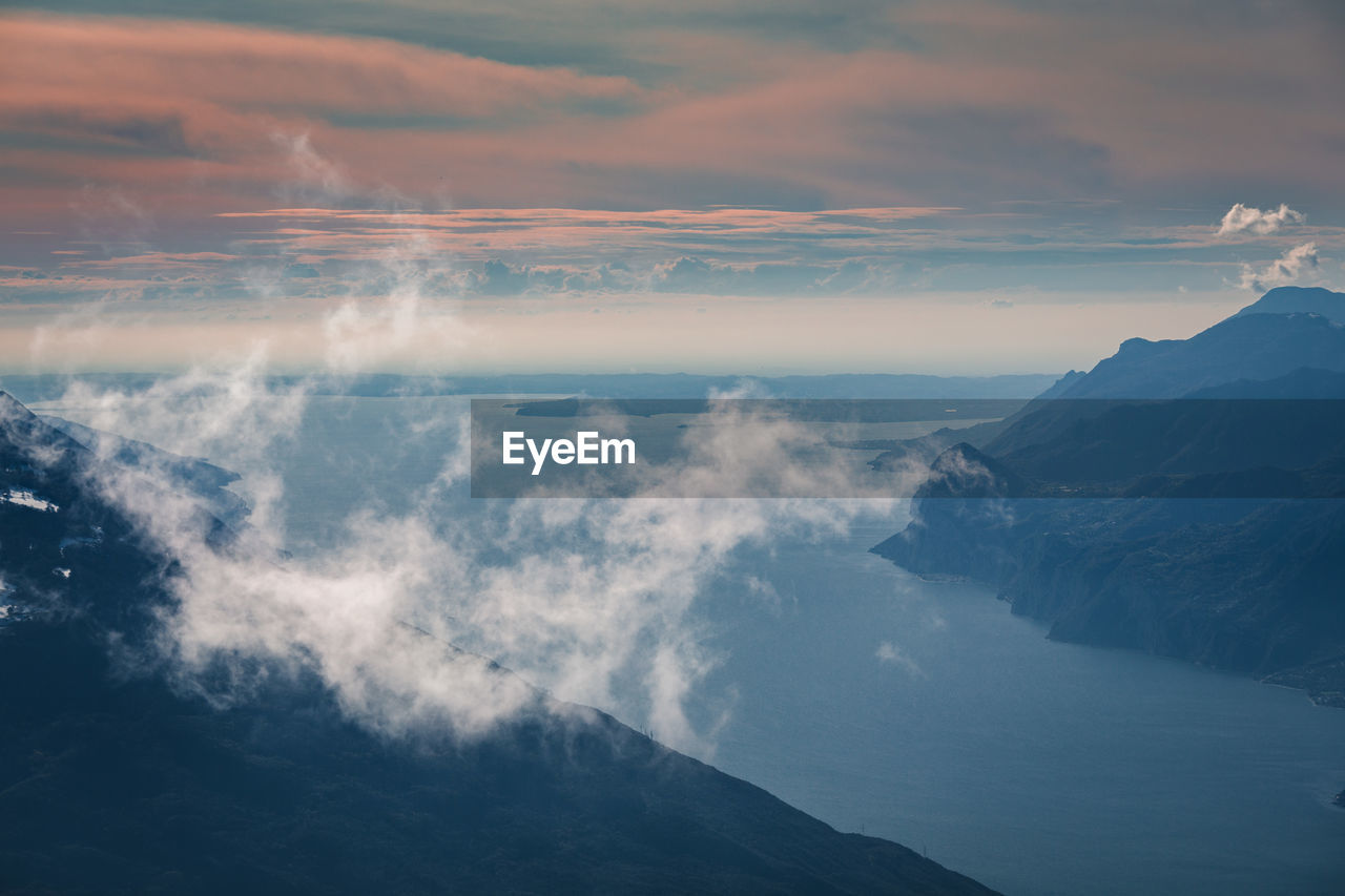 Aerial view of sea and mountains against sky during sunset