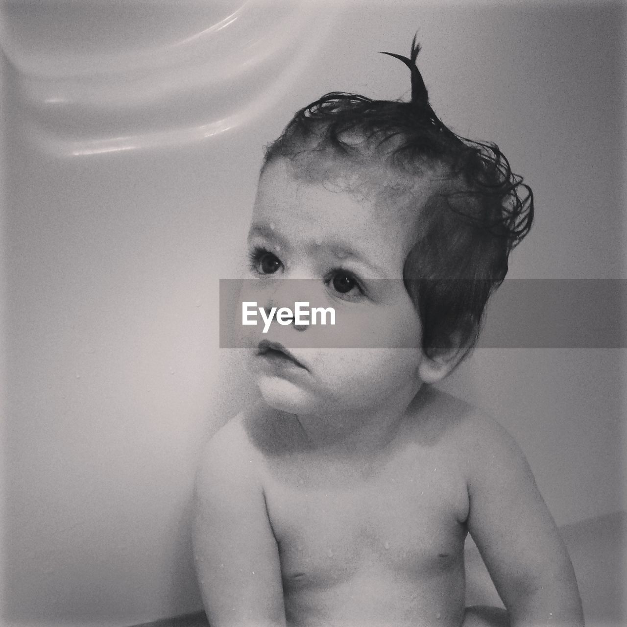 Close-up of baby boy looking way while sitting in bathroom