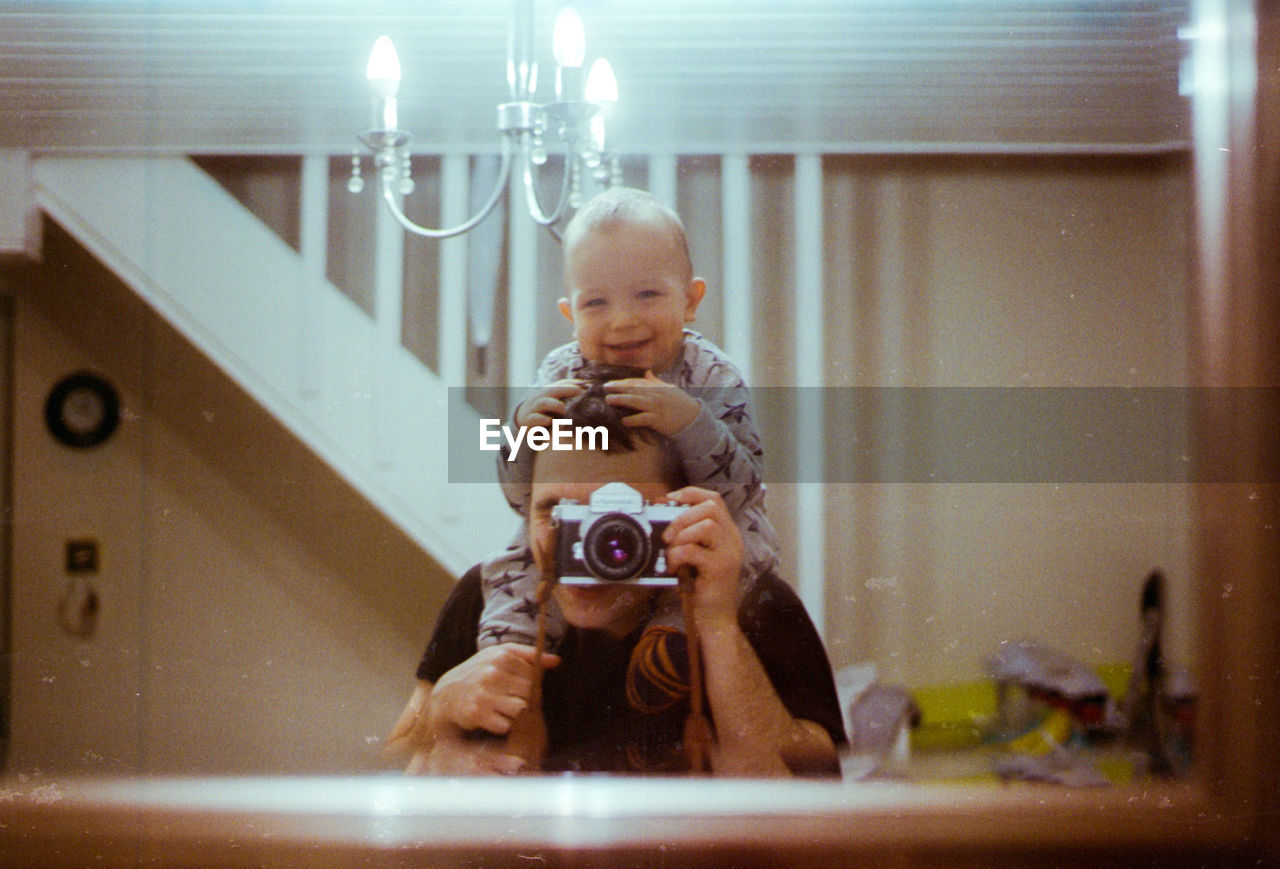 PORTRAIT OF GIRL HOLDING CAMERA IN BATHROOM