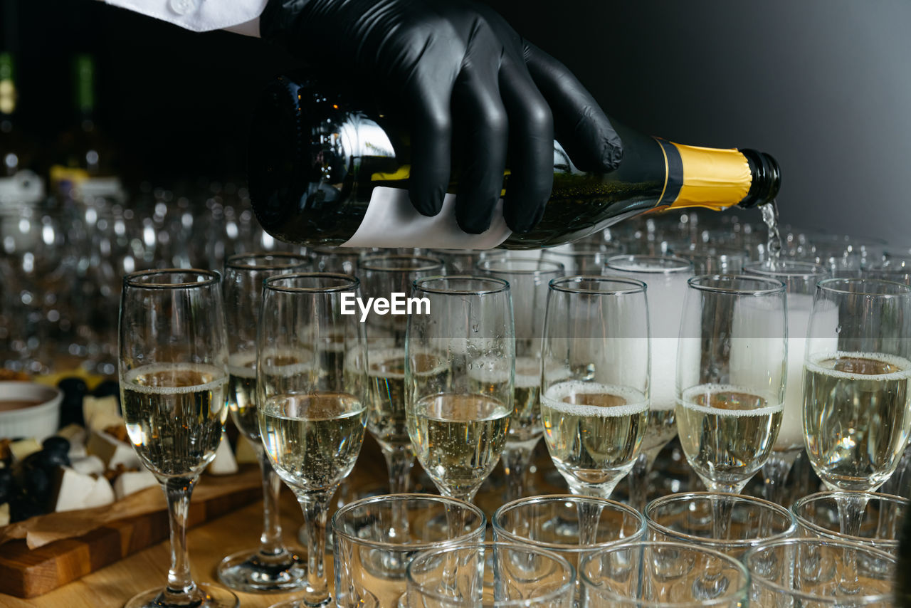 Waiter pours champagne into glasses, close-up of the hands. party drinks. luxury raw of alcohol.