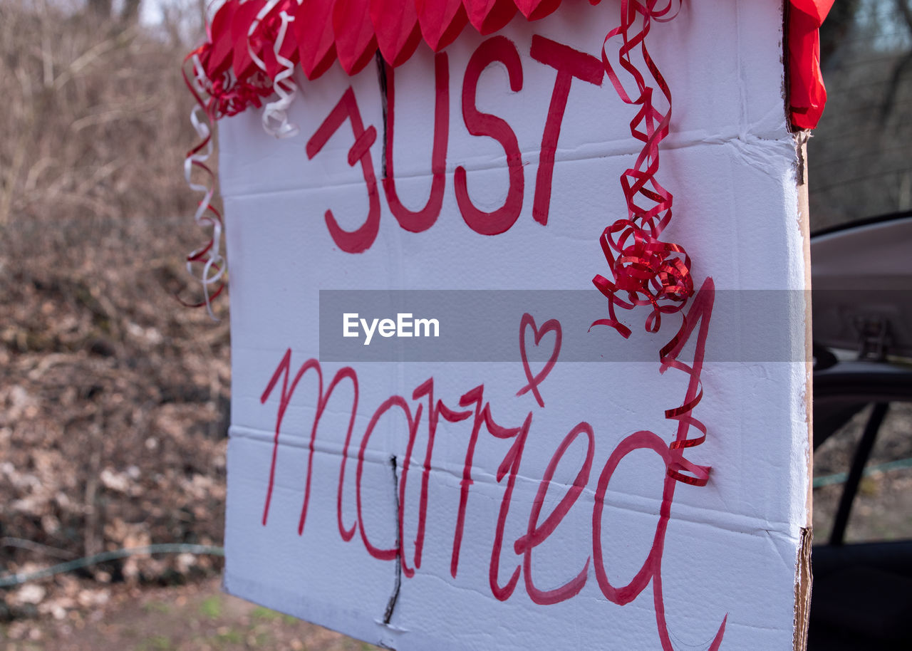 CLOSE-UP OF TEXT ON RED HEART SHAPE SIGN ON WOOD