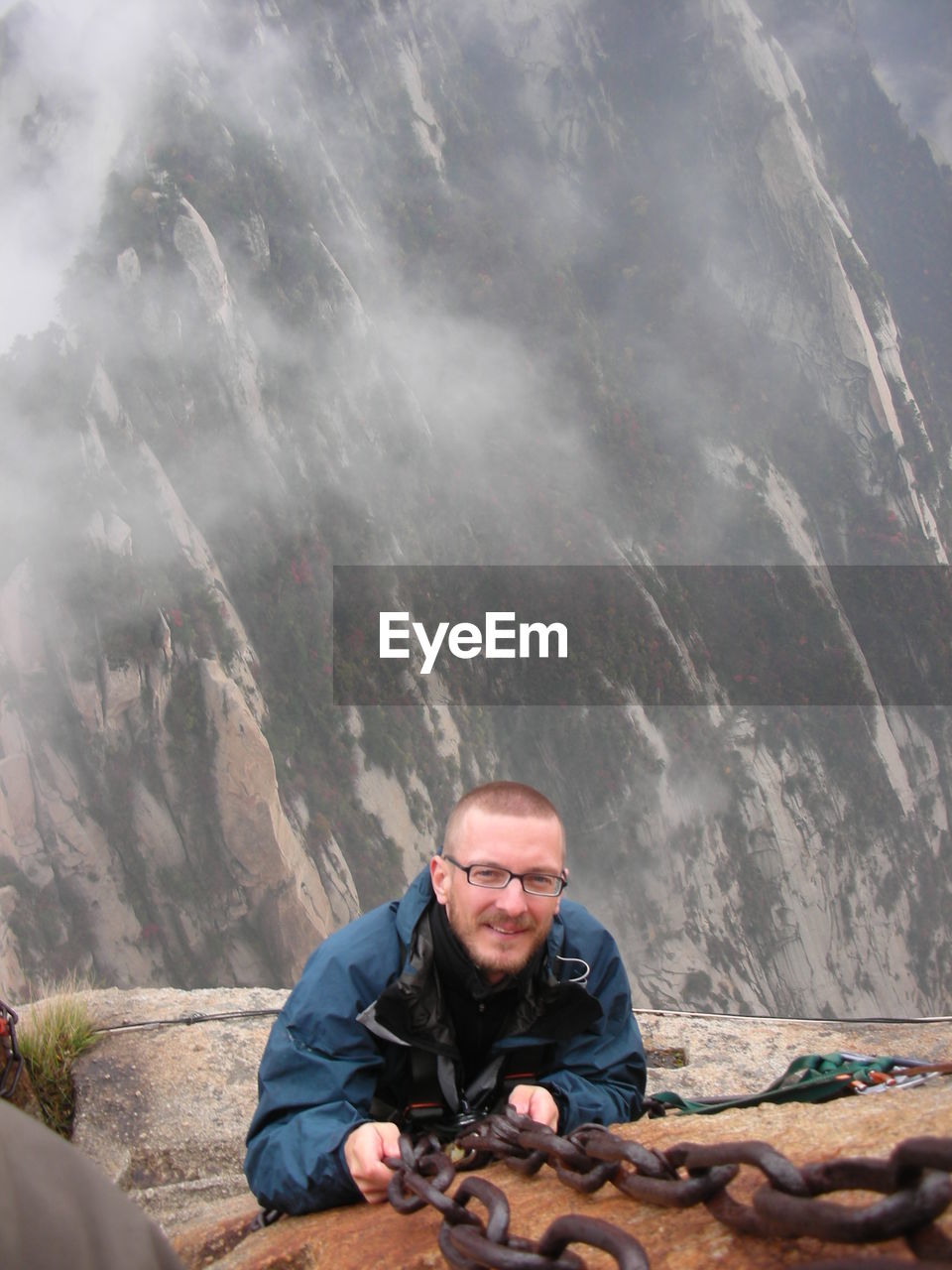 High angle portrait of man holding chain while climbing rock